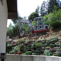 Bagger steht auf einer Erhöhung in einem Garten